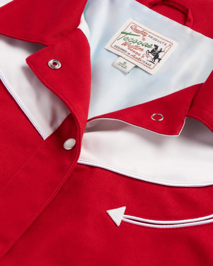 Close-up of a red and white western-style shirt with pearl snap buttons, a pointed pocket detail, and a visible label reading "Ranch Wear" by Rockmount Ranch Wear.