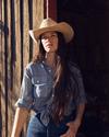 Woman wearing the ranchman hat in silverbelly standing in a barn doorway