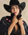 Person wearing a black wide-brimmed hat and a black embroidered jacket with rose details, holding the collar and looking at the camera.