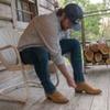 Man leaning down adjusting cream boots on porch
