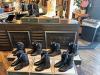 A variety of cowboy boots displayed on a wooden counter and floor in a retail store setting.