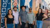 A group of people standing in front of a mural.