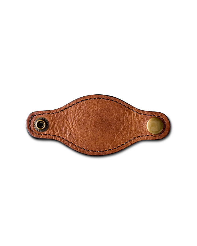 A brown leather keychain with a brass snap button and an eyelet on a black background.