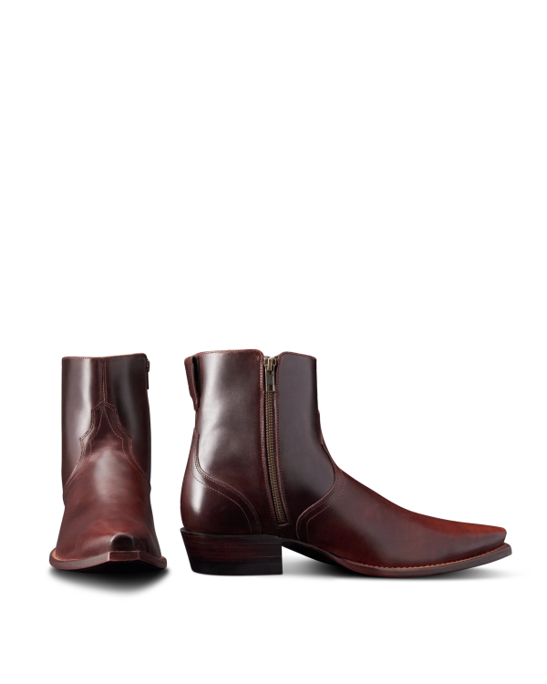 Two brown leather ankle boots with zippers, featuring a slight heel and a pointed toe, are displayed against a plain background.