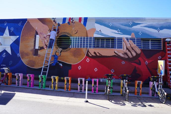 backed up view of the mural of Willie Nelson hand playing guitar