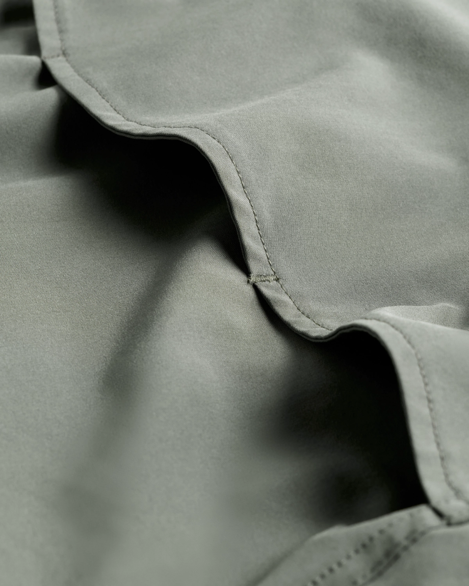 Close-up of light green fabric with visible stitching and soft folds.