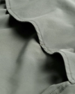 Close-up of light green fabric with visible stitching and soft folds.