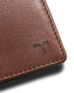Close-up of a brown leather material with visible stitching and a small embossed logo in the corner.