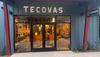 Storefront of Tecovas, featuring large illuminated signage, glass doors, and displays of cowboy boots inside.