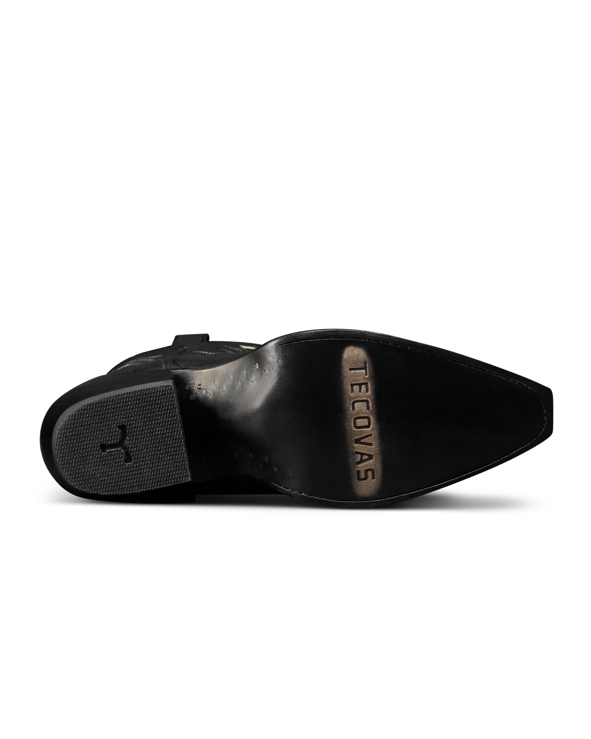 The Annie in Midnight Cowhide. The underside of a Midnight Cowhide black dress shoe showing a pointed toe, textured heel, and the brand name "Tecovas" engraved on the sole.