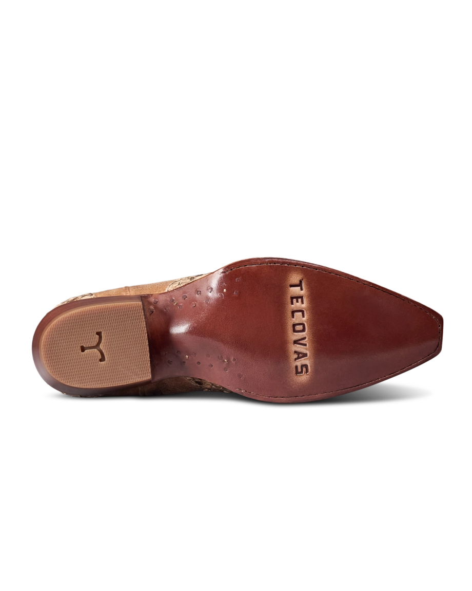 The Loretta in Mangrove Invasive Python. The underside of a brown cowboy boot with a pointed toe, showing a textured rubber heel and the word "Tecovas" stamped on the leather sole—crafted in The Loretta Invasive Python for a unique blend of style and resilience.