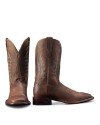 A pair of brown leather cowboy boots with decorative stitching, one boot standing upright and the other laying on its side, on a white background.