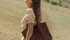 Woman in a field carrying a leather tote bag