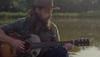 man playing guitar by water