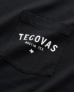 Close-up of a black shirt pocket with white text reading "Tecovas Austin, Tex." and a small Texas state outline below.
