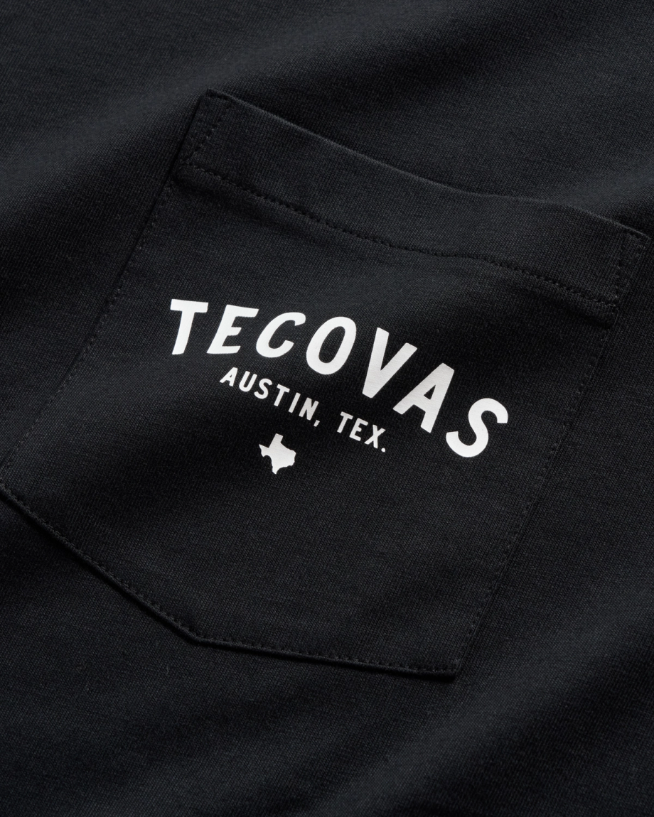 Close-up of a black shirt pocket with white text reading "Tecovas Austin, Tex." and a small Texas state outline below.