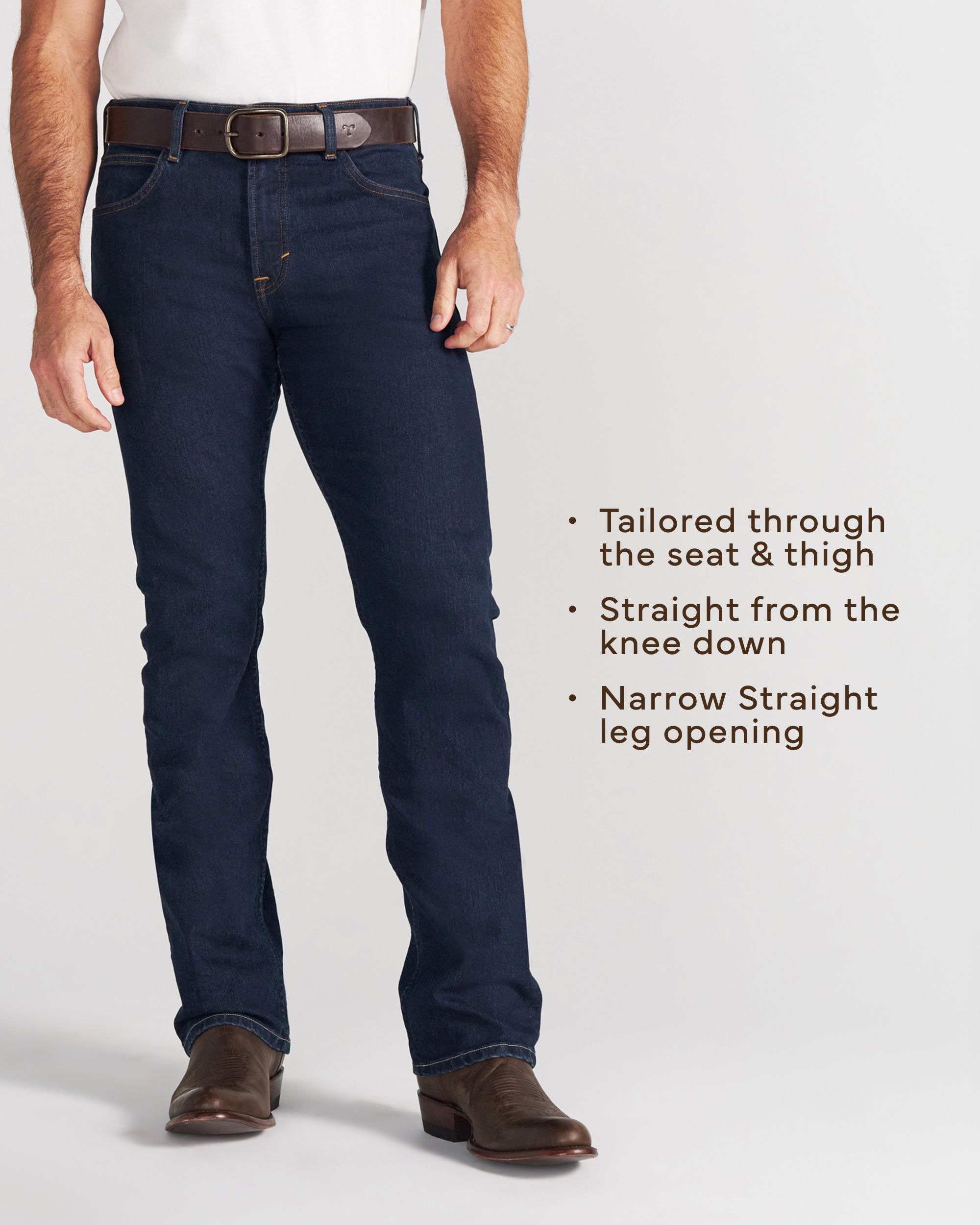 A person wearing a white short-sleeve shirt, blue jeans, and brown boots stands with one hand in their pocket against a plain background.