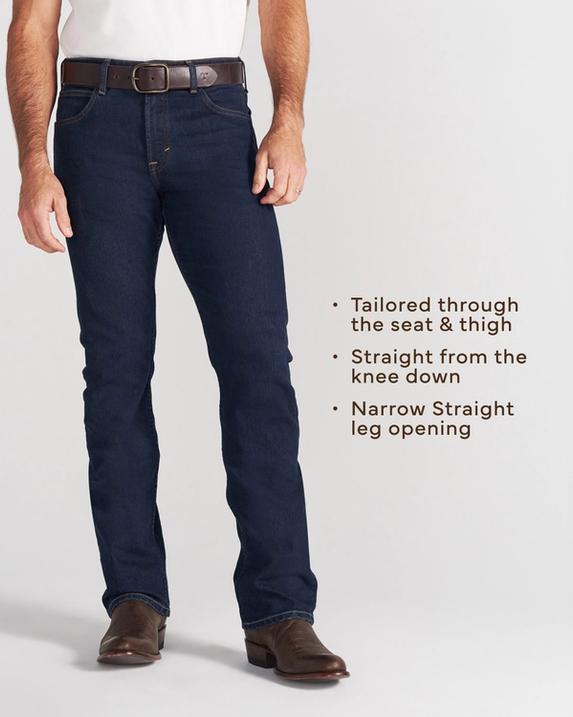 A person wearing a white short-sleeve shirt, blue jeans, and brown boots stands with one hand in their pocket against a plain background.