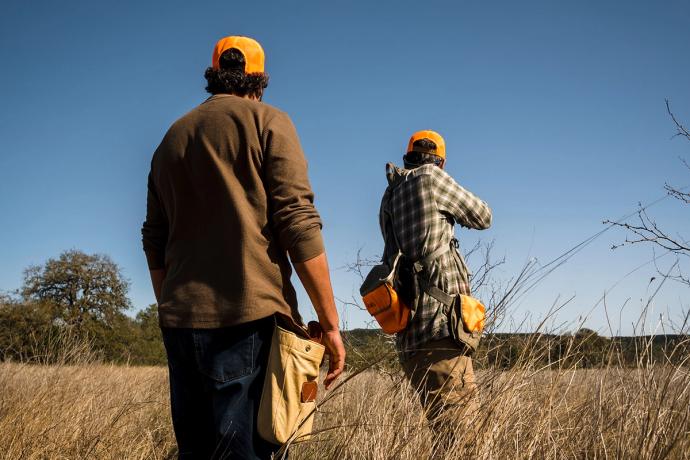 two hunters from behind, aiming with a gun