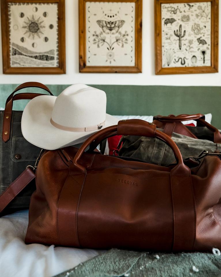 brown leather duffel bag, cowboy hat