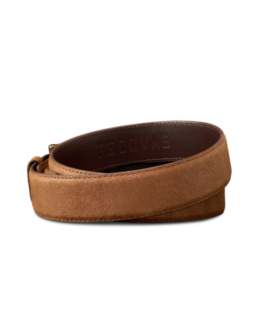A brown leather belt with a suede finish, coiled and showing the embossed word "Tecovas" on the inner side.