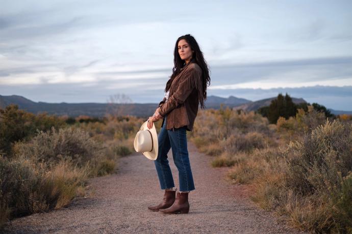 woman standing on a trail with a cowgirl hat