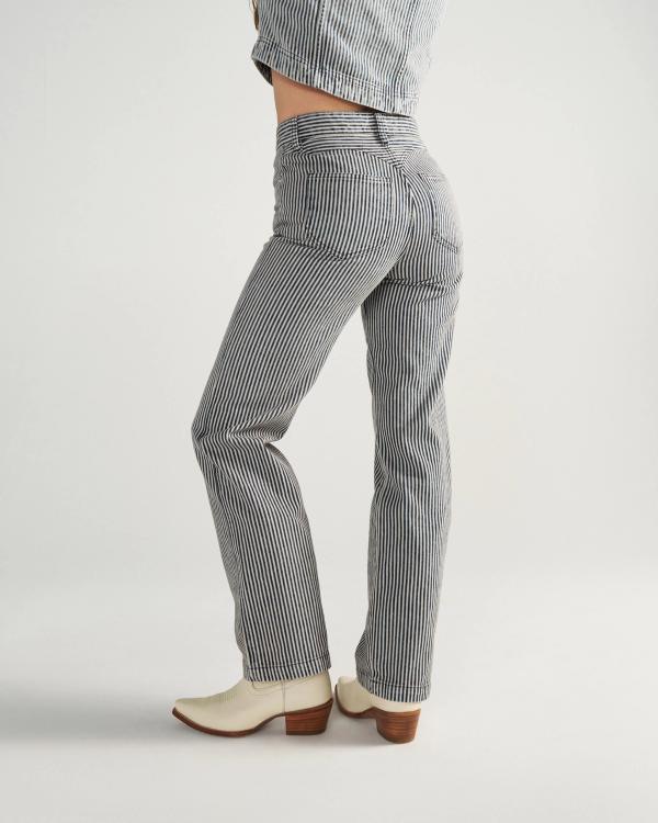 Person wearing striped pants, a matching jacket, and white heeled boots, standing sideways against a plain background.