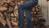 Man in jeans and boots in front of chopped wood
