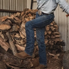 Man in jeans and boots in front of chopped wood
