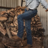 Man in jeans and boots in front of chopped wood