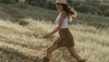 Woman in mini skirt and The Annie cowgirl boots walking through a field