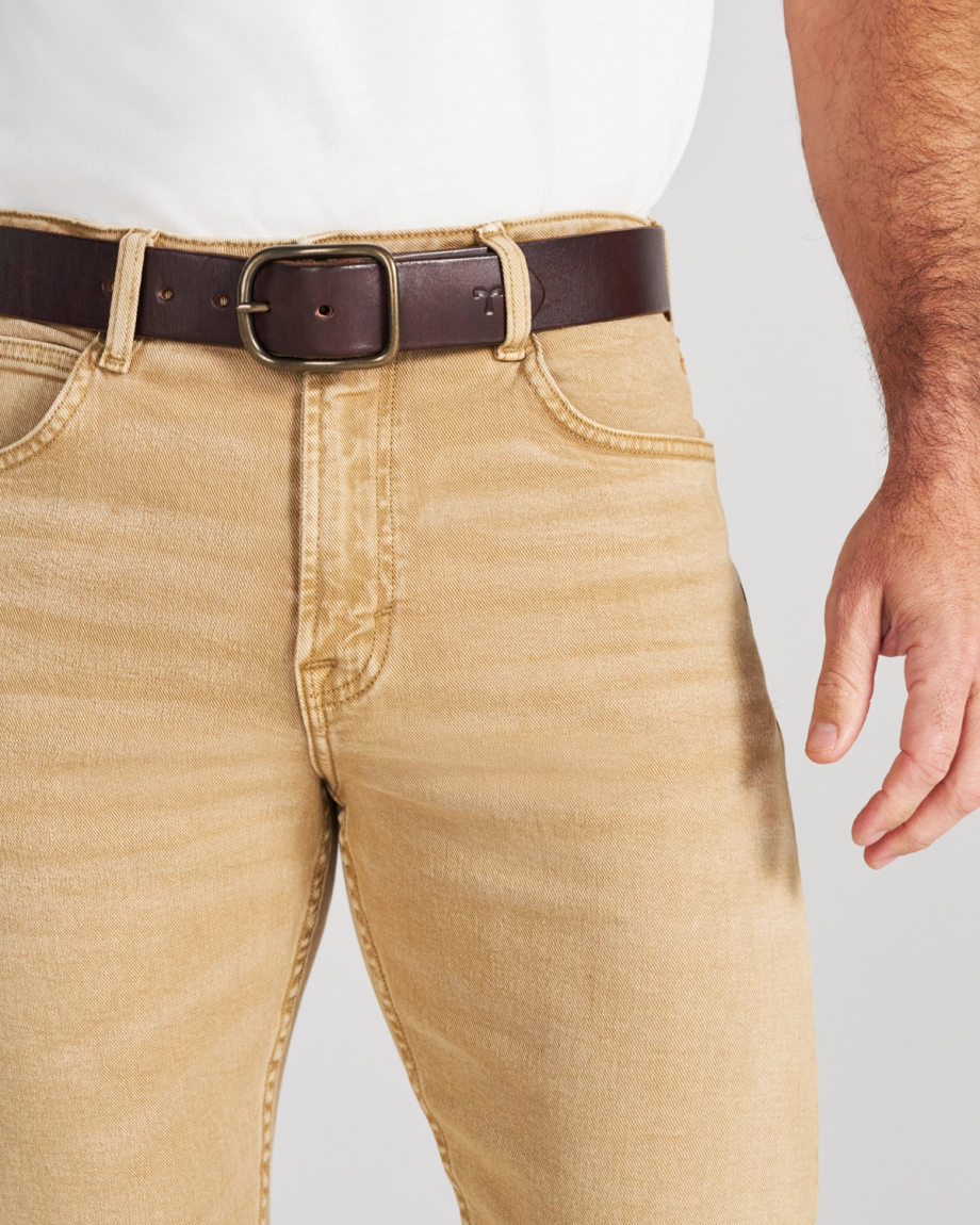Tan jeans worn with a brown leather belt over a white shirt.