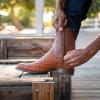 Man zipping up boot on wood step