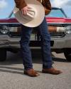 Man holding cowboy hat standing near a car