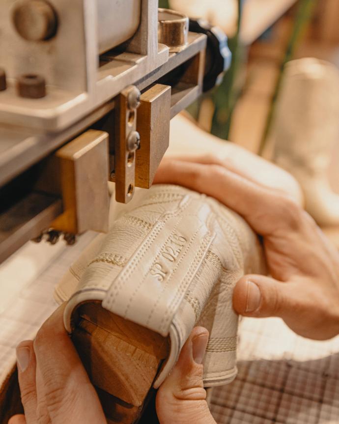 Craftsperson embossing a pattern onto a piece of fabric with a machine.