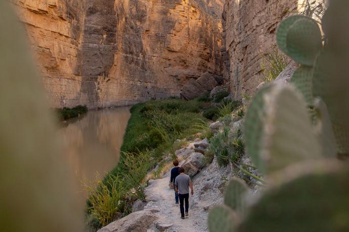 men walking on a trail between rock cliffs in west texas landscape