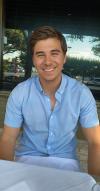 A young man in a blue shirt smiling at a table.