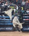 A rodeo rider holds onto a bucking bull in an arena, surrounded by barriers and spectators during a bull riding event.