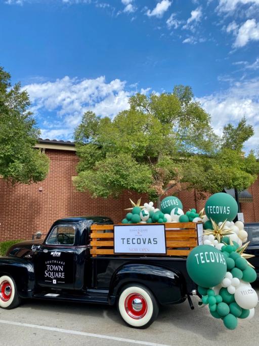 Vintage truck with a basket of balloons with Tecovas logo