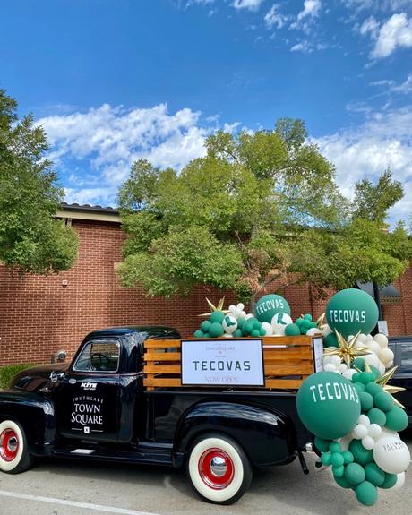 Vintage truck with a basket of balloons with Tecovas logo