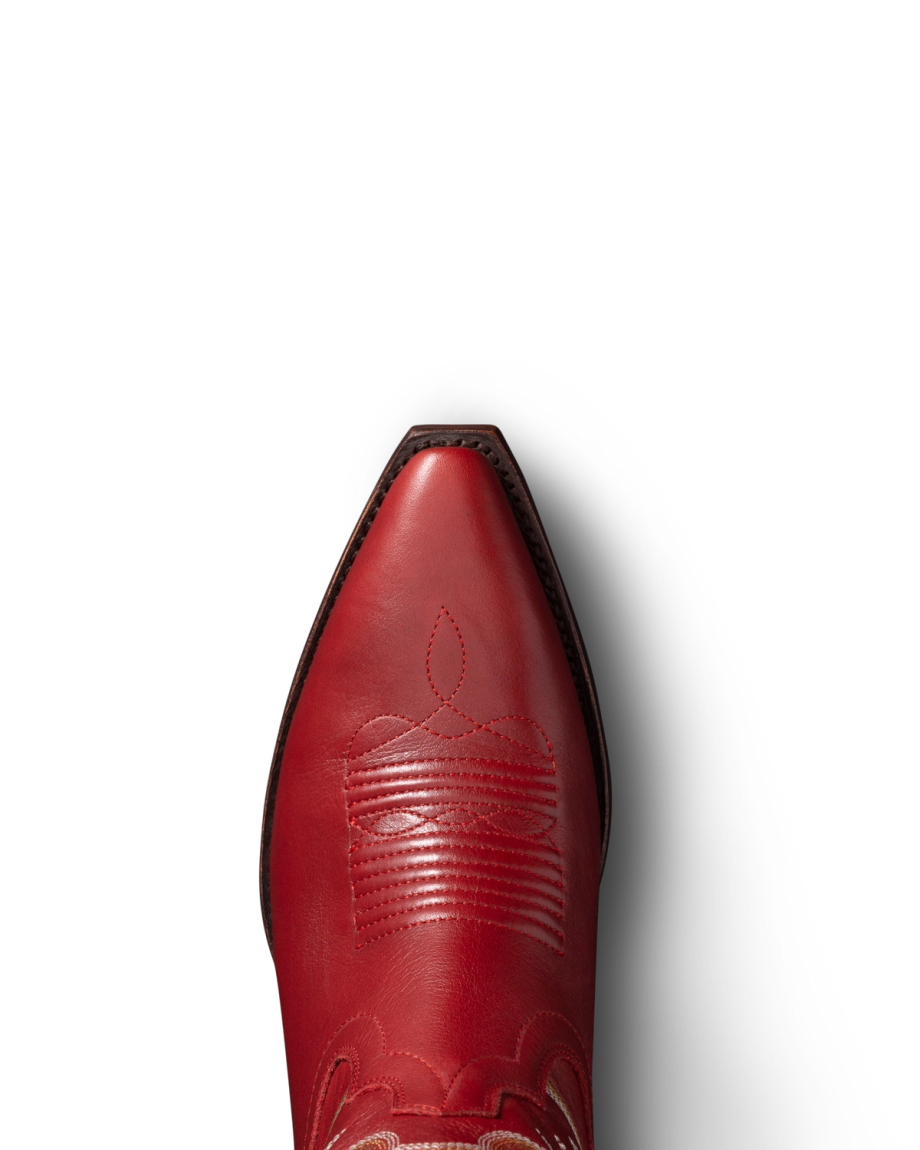 Close-up view of a red cowboy boot with intricate stitching, set against a black background.