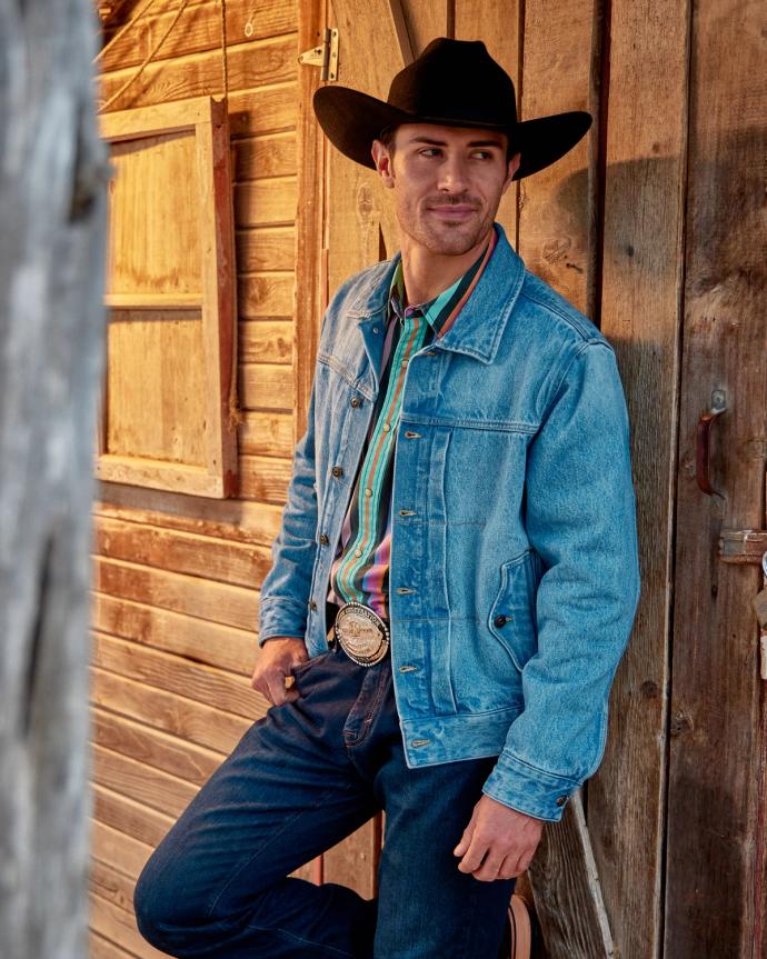 Man leaning against a wall wearing denim