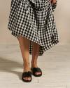 Closeup of woman wearing black sandals with a gingham dress