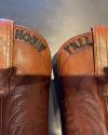 A pair of leather cowboy boots with the words "howdy" and "y'all" embossed on the front shafts.