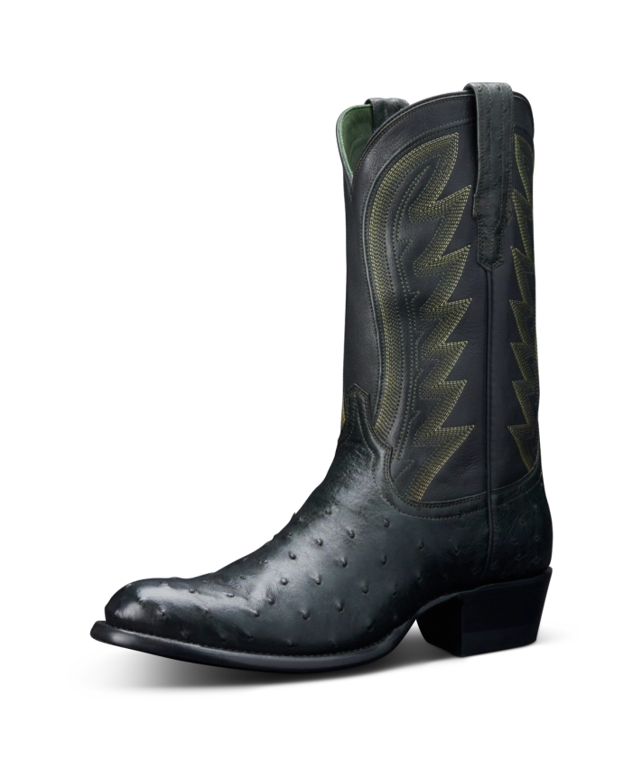 A single black cowboy boot with decorative stitching and a short heel, set against a black background.