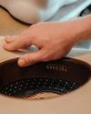 A person’s hand rests on a beige hat with a visible brown leather inner band labeled “TECOLAS,” showing part of the patterned hat lining.