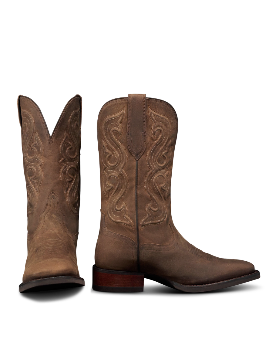 The Tess in Cafe Goat. A pair of brown leather cowboy boots with decorative stitching, inspired by The Tess Goat, one boot standing upright and the other displaying the front view.