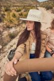 Woman wearing a straw hat sitting in a jeep in the desert