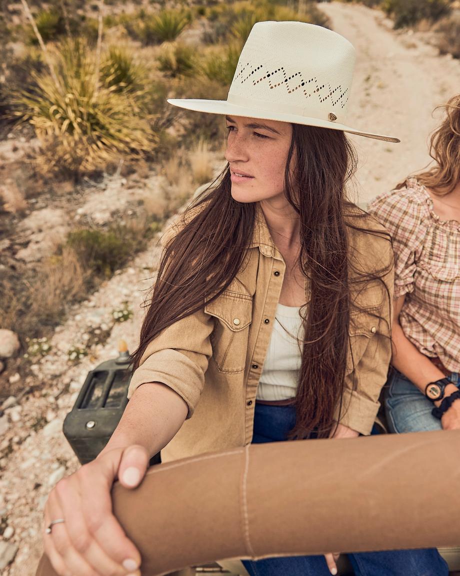Woman wearing a straw hat sitting in a jeep in the desert