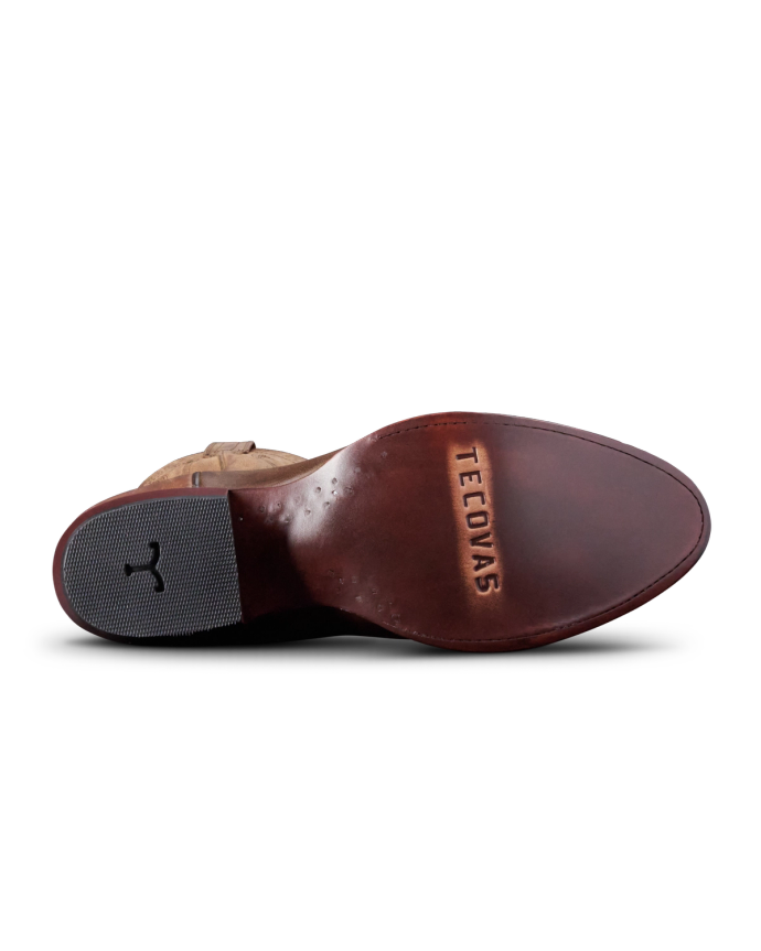 Underside view of a brown leather shoe with "Tecovas" engraved on the sole and a textured heel.